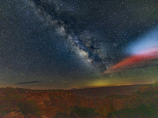 Milky Way and bright lighes over a canyon
