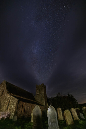 Milky Way above a stone church and a graveyard.