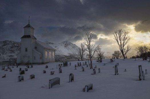 A church and graveyard with sunilght reflected in the church windows
