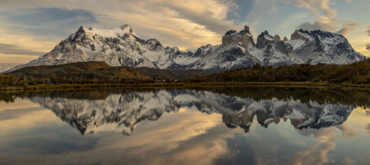 Snow-covered mountains reflected in water.